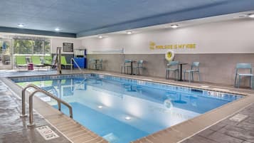 Una piscina interior con agua cristalina, zonas de profundidad señalizadas y un cartel que dice 'Poolside is My Vibe'.