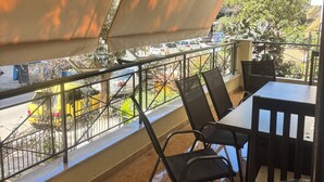Varanda com mesa e cadeiras, vista para a rua e um ventilador de teto.