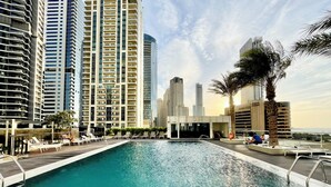Una piscina con lettini e vista su alti edifici sullo sfondo.