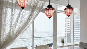 A modern hotel room with a large window, decorative curtains, and two hanging lamps. - Settler.Homes, Breathtaking 2BR Marina, HighFloor (Dubai)