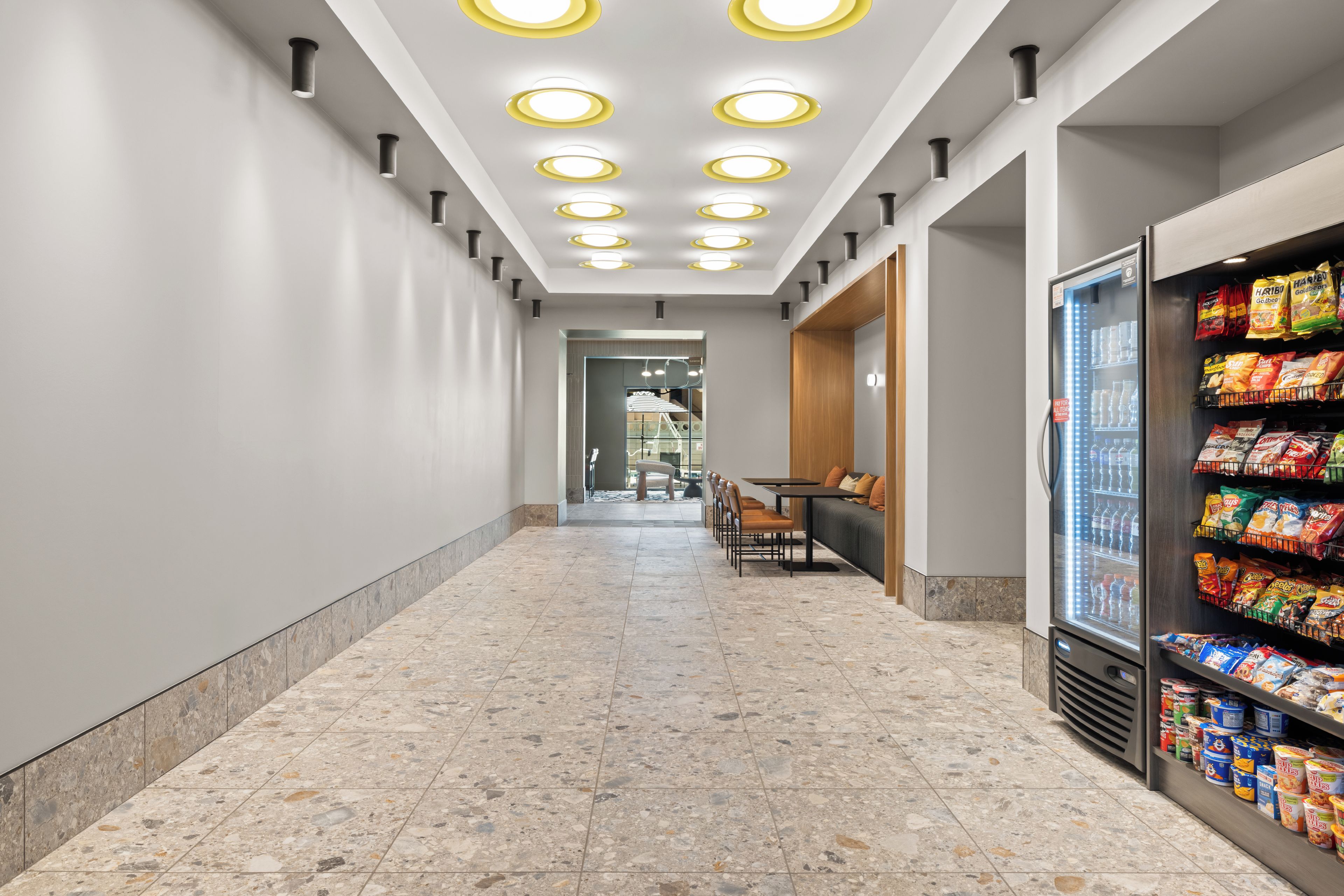 A corridor with a snack vending machine and seating area.