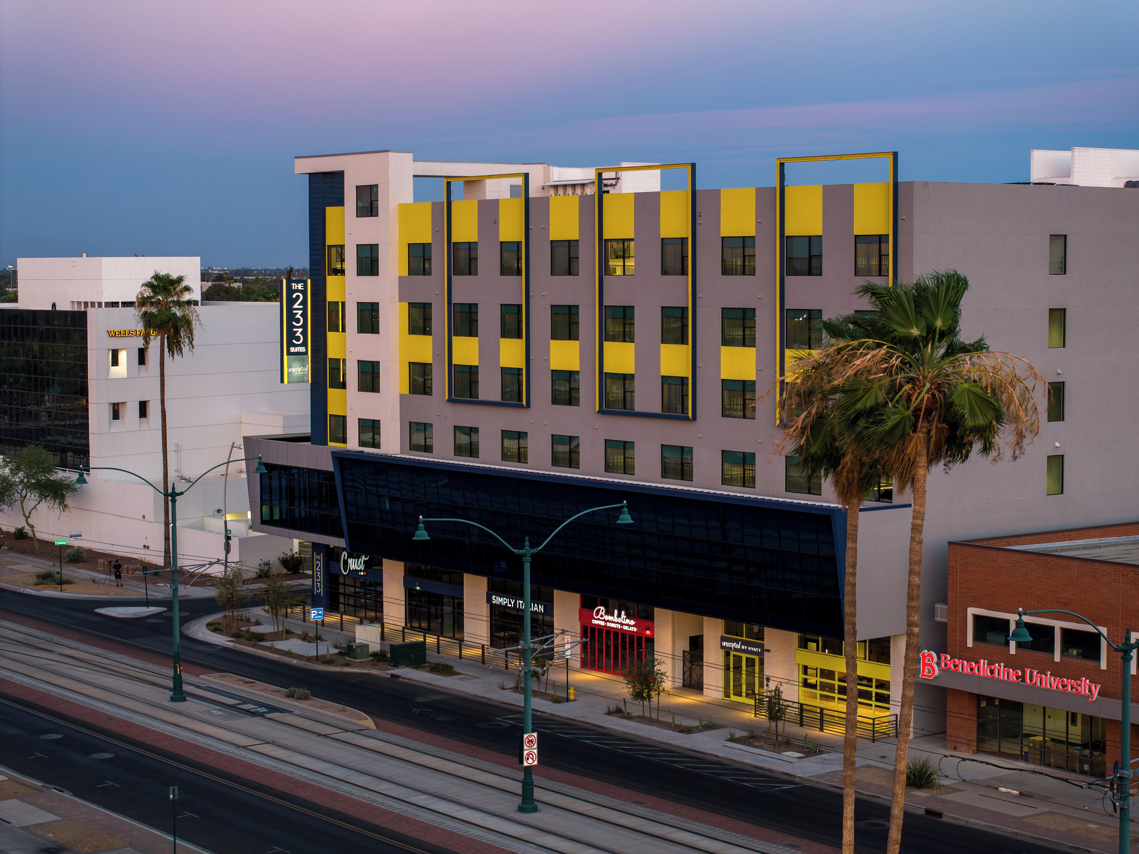 A multi-story hotel with a modern facade, featuring a mix of yellow and grey panels.