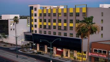 A multi-story hotel with a modern facade, featuring a mix of yellow and grey panels.