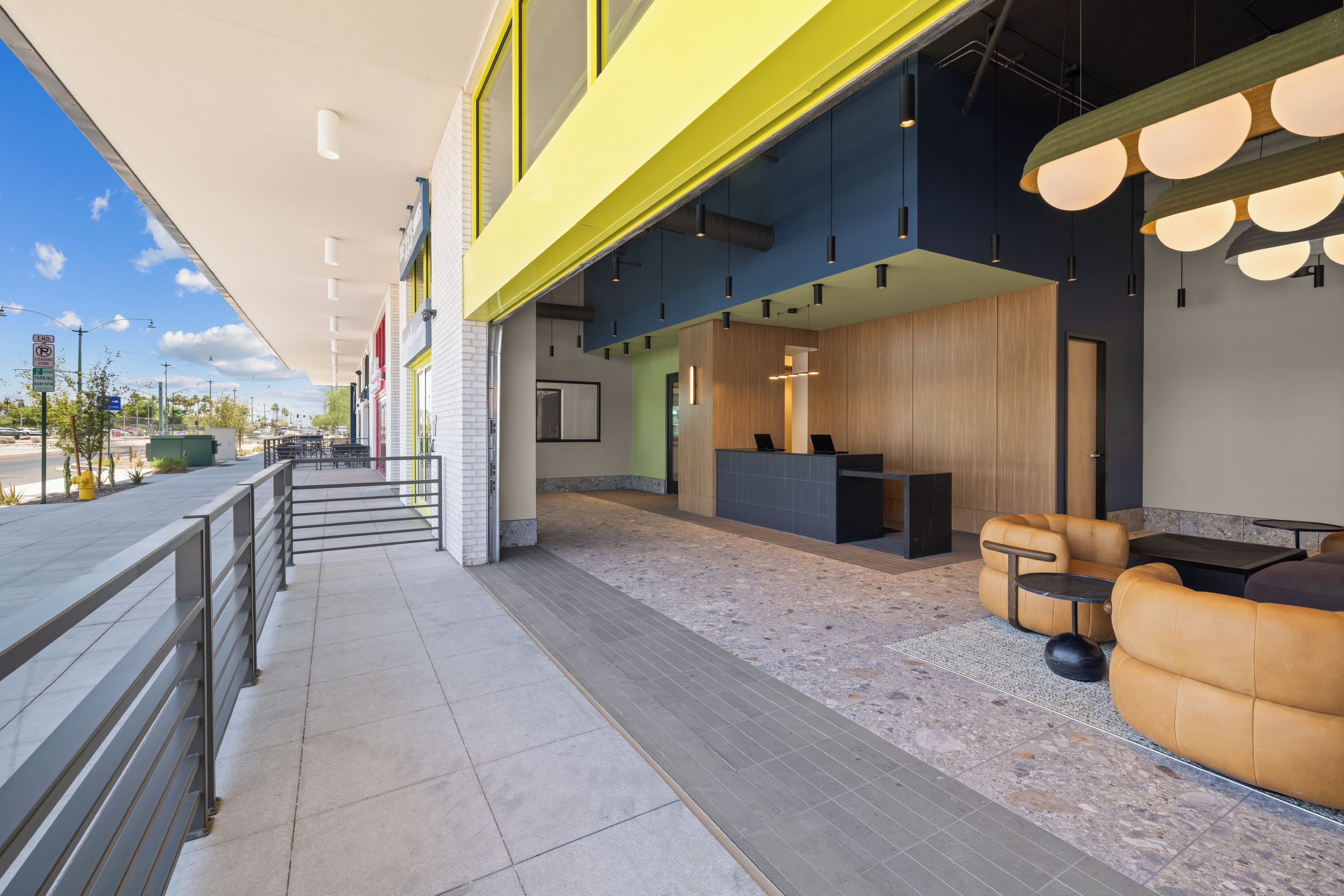 A modern hotel lobby with a reception desk, seating area, and a view of the street.