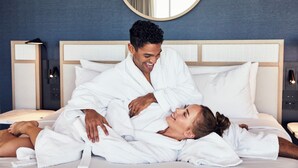 A hotel room with a bed, a bedside table, and a wall-mounted mirror.