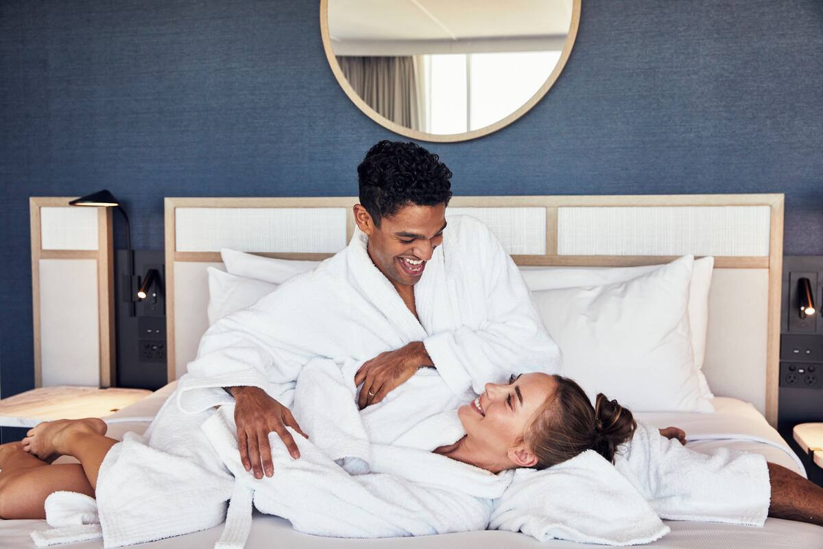 Una habitación de hotel con una cama, un espejo redondo y una mesita de noche.