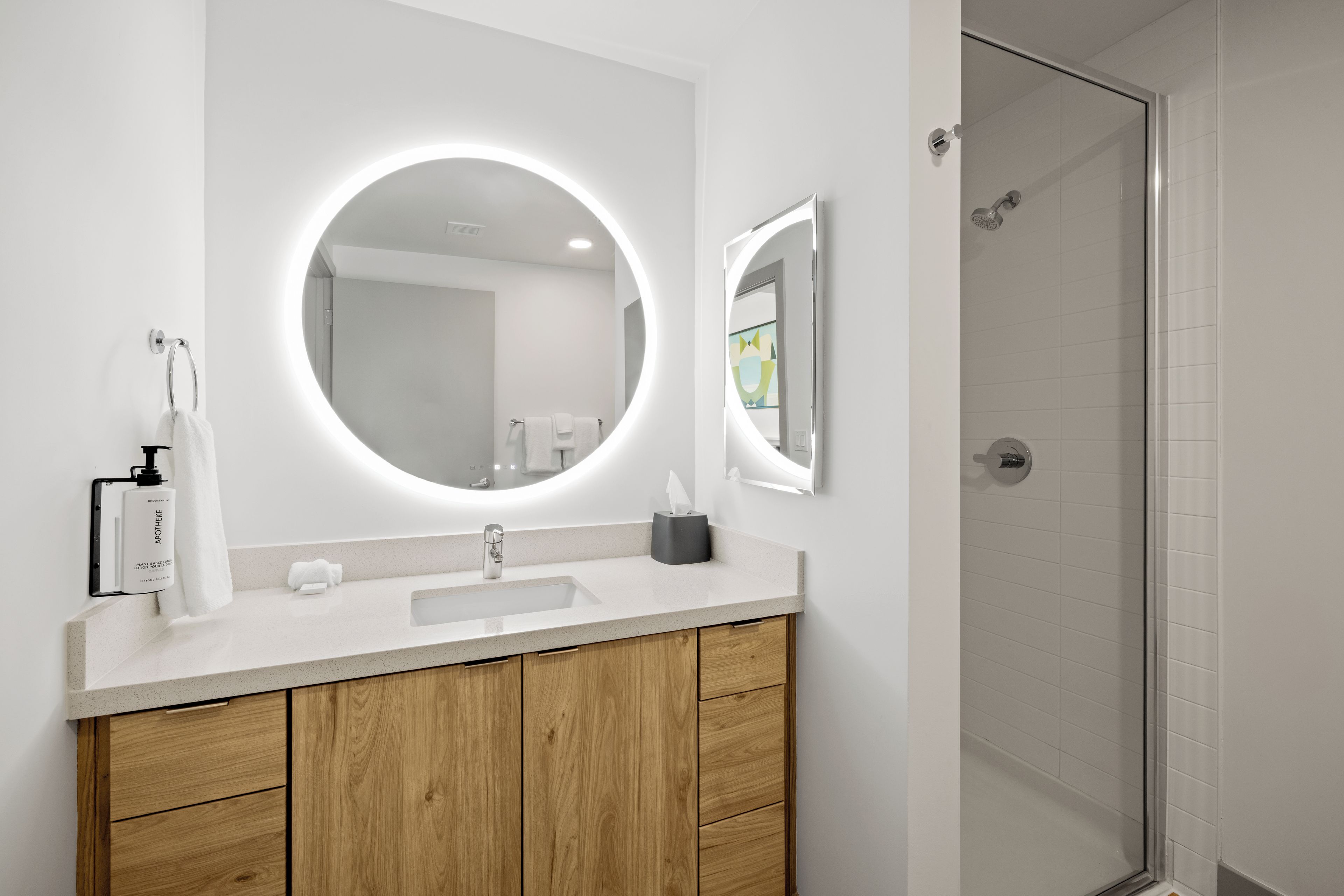 A bathroom with a round mirror, a sink, and a shower.