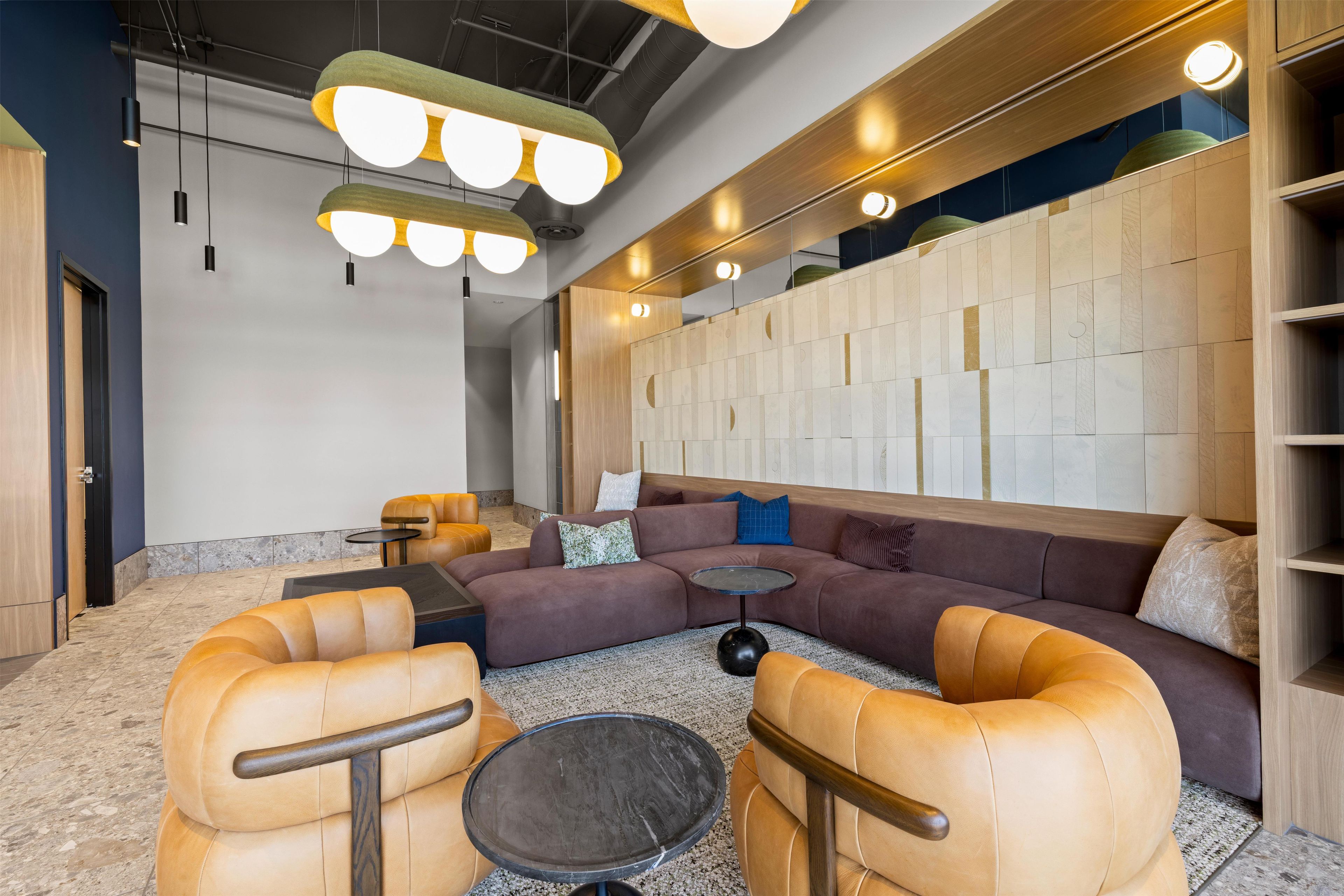 A modern lounge area with leather sofas, a round coffee table, and pendant lighting.