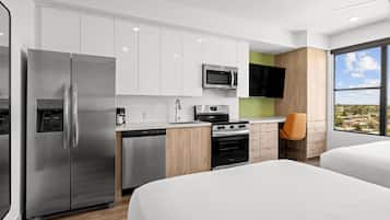 A modern kitchen with a refrigerator, microwave, stove, and dishwasher. There is a window with a view of the outside.