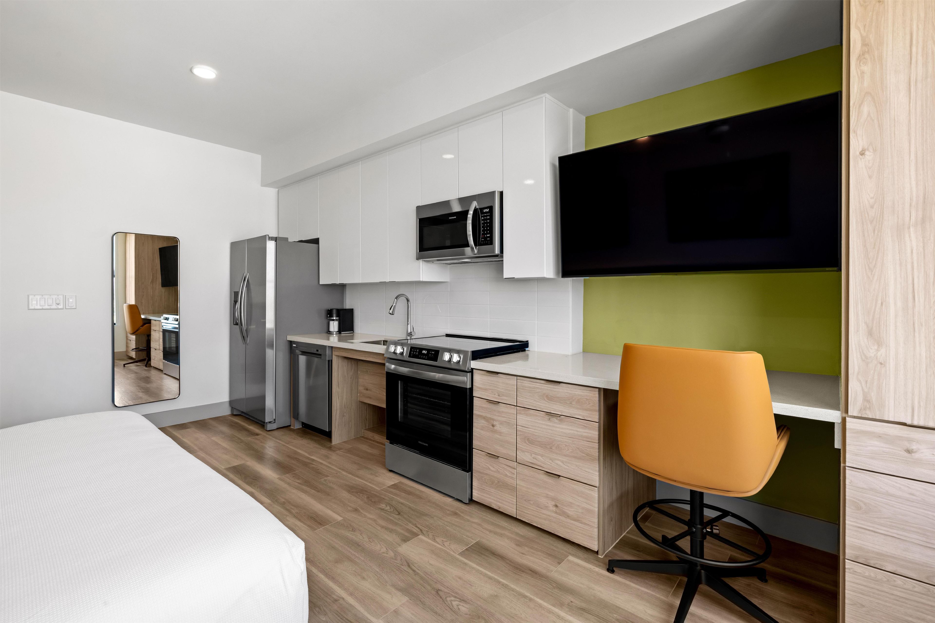 A modern kitchen with white cabinets, a stainless steel refrigerator, a microwave, and an oven.