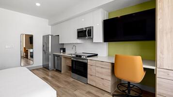 A modern kitchen with white cabinets, a stainless steel refrigerator, a microwave, and an oven.