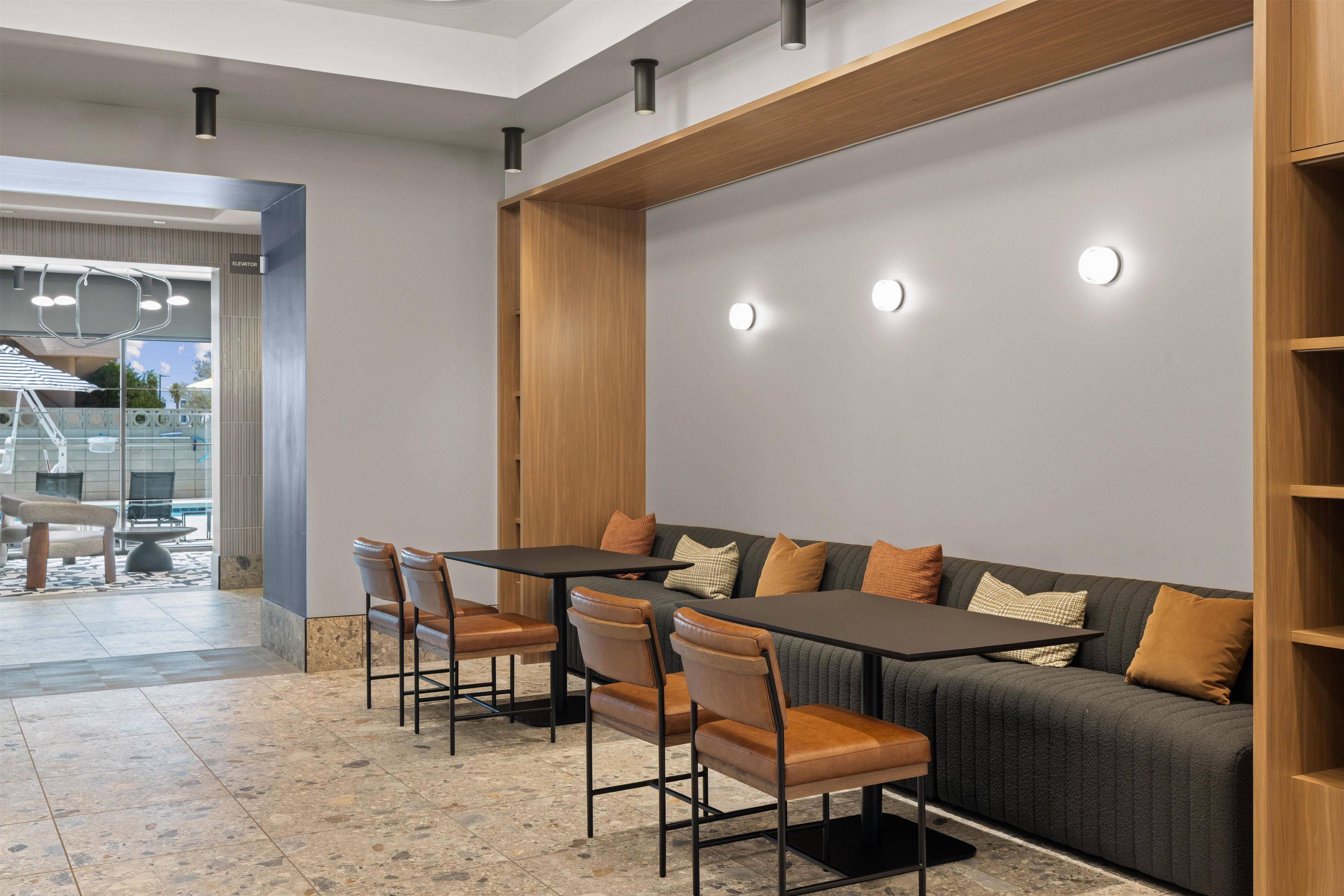 A modern dining area with a black table and brown chairs, a grey sofa with cushions, and a wooden accent wall.