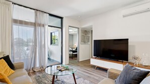 A modern living room with a flat-screen TV, a glass coffee table, and a sofa. - The Beaufort Street Nook (Perth)