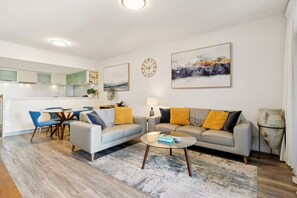 A modern living room with a sofa, coffee table, and dining area. - The Beaufort Street Nook (Perth)