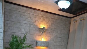 A cozy living room with a brick wall, a sofa, a small table, and a potted plant. - Casa SOLENO-Apartment in Heredia, urban comfort with views of nature (Heredia city)