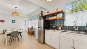 A modern kitchen with white cabinets, a stainless steel refrigerator, and a window with a view of greenery. - Walkable Rincón Paradise near Plaza & Beaches w/ Carport (Rincon)