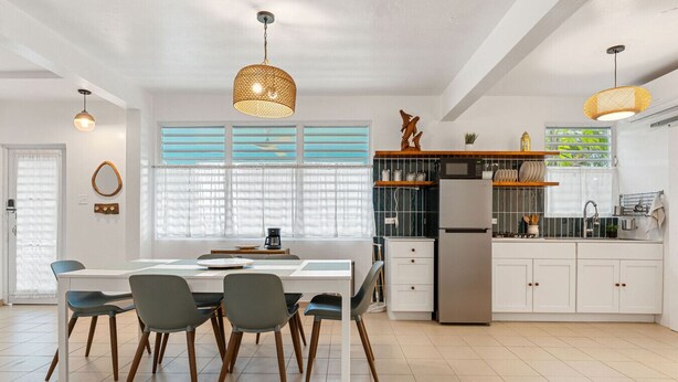 A modern kitchen with a dining area, featuring a central island, pendant lights, and a refrigerator. - Walkable Rincón Paradise near Plaza & Beaches w/ Carport (Rincon)