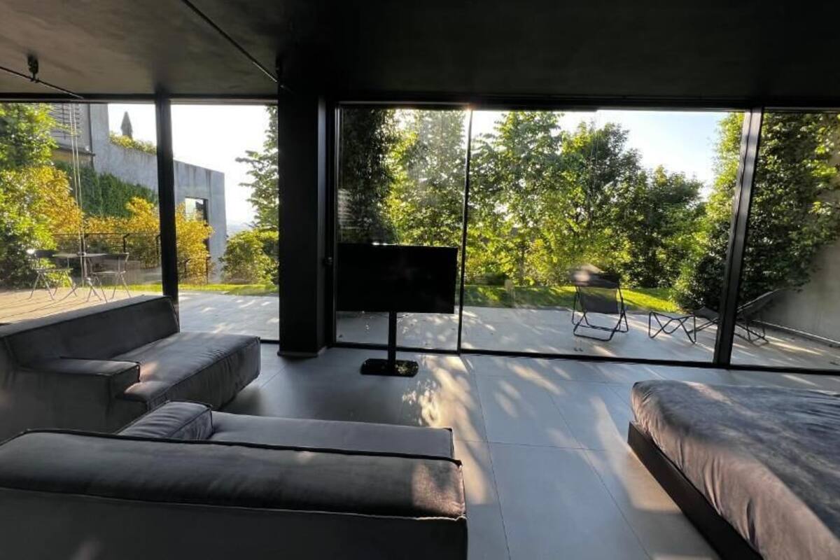 Una camera moderna con ampie finestre, un divano, un letto e una televisione a schermo piatto.