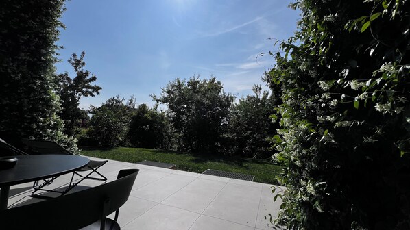 An outdoor patio with a table and chairs, surrounded by greenery and trees. - Murraeloft (La Morra)