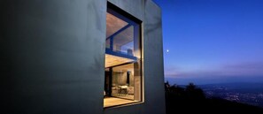 A modern building with a large window revealing a room with a wooden floor and a table. - Murraeloft (La Morra)