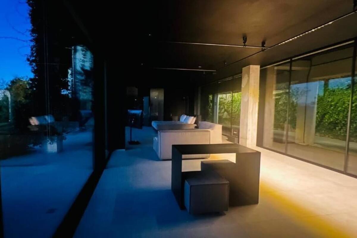Un interno moderno con un divano, un tavolino da caffè, ampie finestre e vista sul verde.