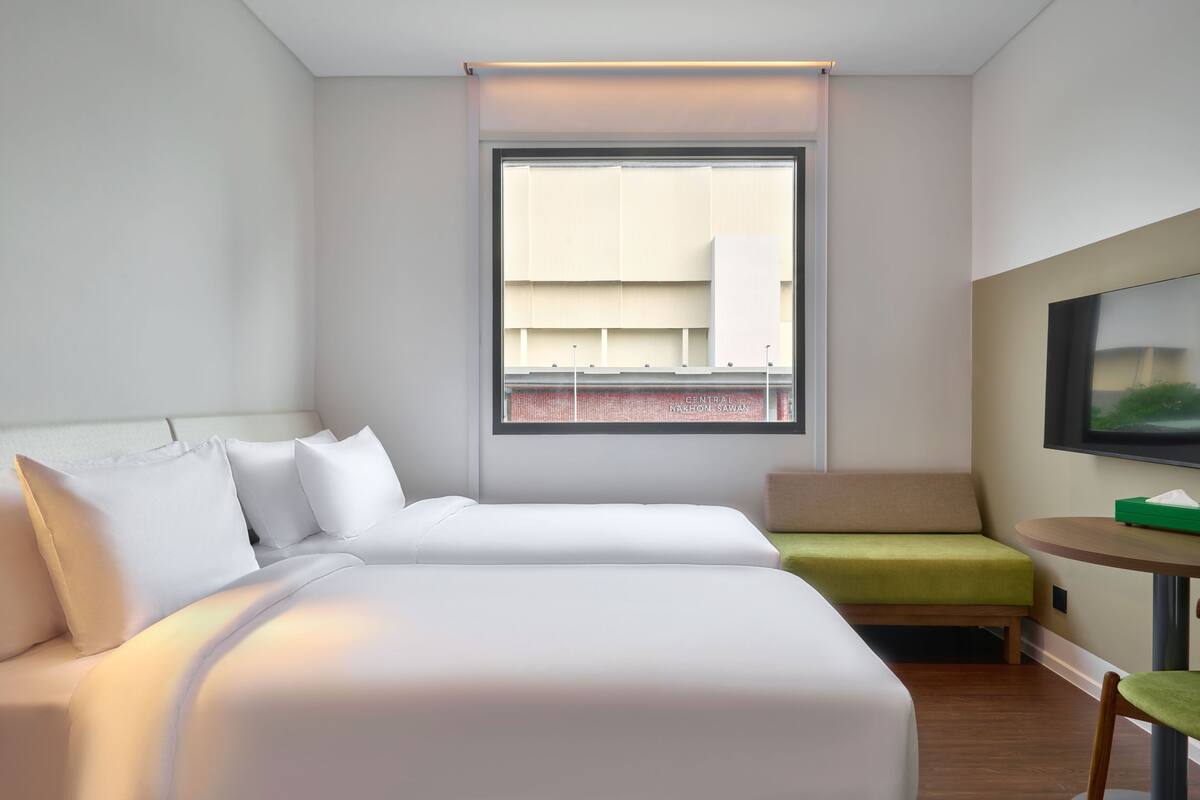 Une chambre d’hôtel avec un lit, une petite table, une chaise et un téléviseur.
