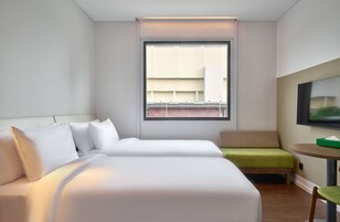 Una habitación de hotel con una cama, una mesita, una silla y un televisor.
