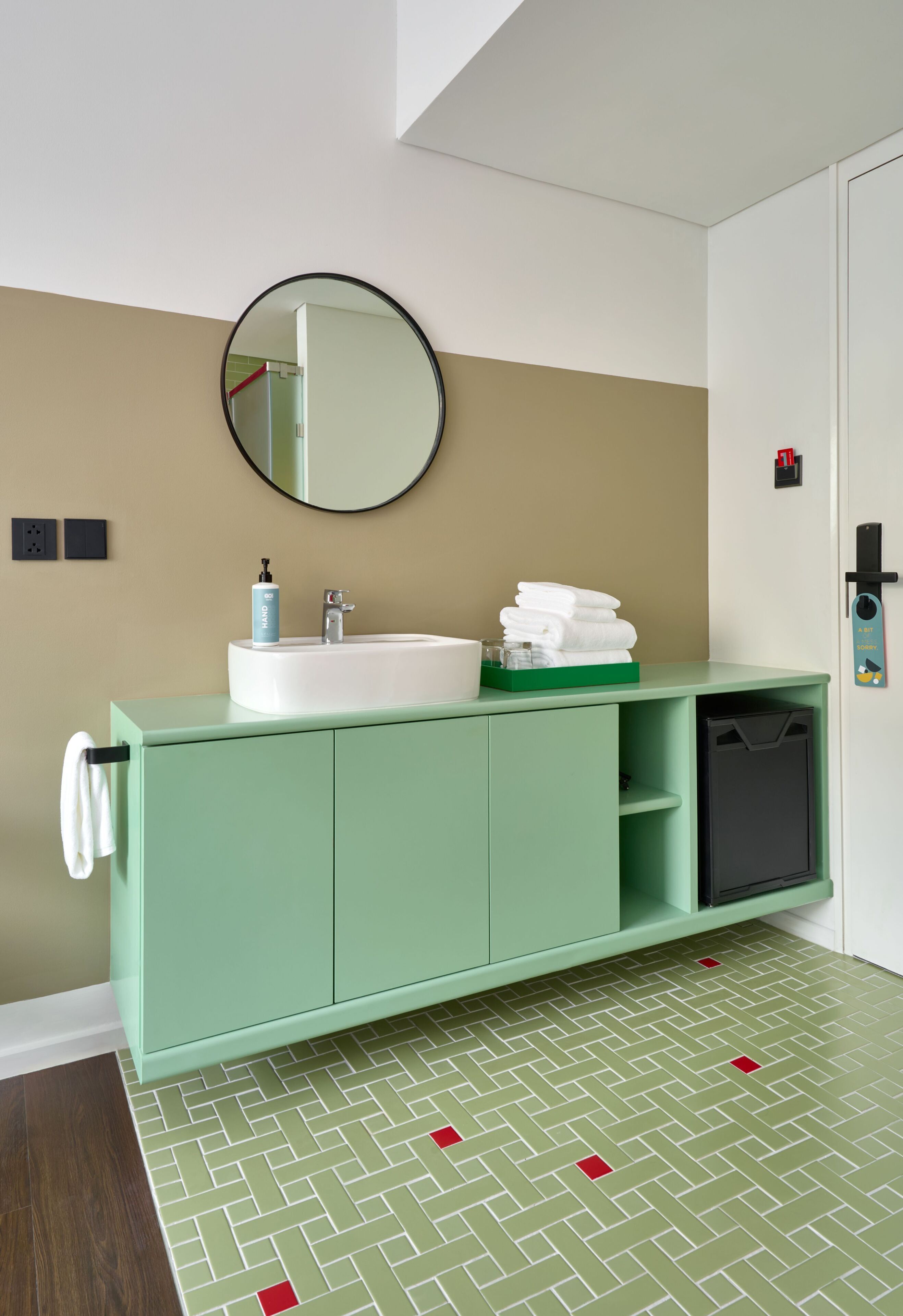 Un baño con tocador verde, lavabo blanco y un espejo.