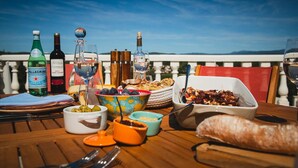 Tavola imbandita con diversi piatti, bottiglie di vino e bicchieri, con vista su un panorama suggestivo.
