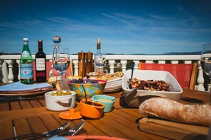 A table set for a meal with various dishes, wine bottles, and glasses, overlooking a scenic view. - Villa Christine, with pool and views in Provence (Carcès)