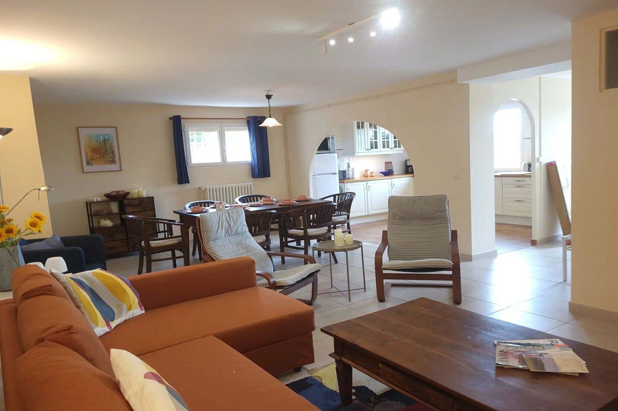 A living room with a sofa, a coffee table, and a dining area with chairs and a table.