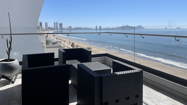 A balcony with a view of the beach and city skyline.