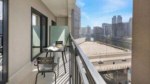 A balcony with a table, chairs, and a view of a cityscape and river. - Canal View 1BR Near Business Bay Metro (Dubai)