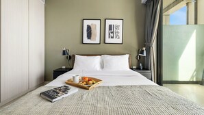 A neatly made bed with white linens, a tray with breakfast items, and two framed artworks on the wall. - Canal View 1BR Near Business Bay Metro (Dubai)