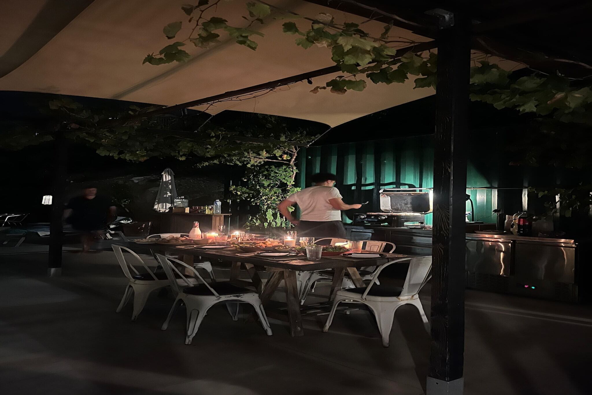 Un espace de restauration en plein air avec une table dressée pour deux personnes, sous une tonnelle.
