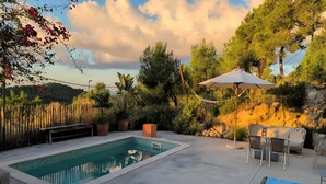 Une piscine dotée d’une terrasse carrelée, entourée de mobilier d’extérieur et d’un grand parasol.