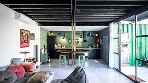 Un salon moderne avec un canapé, un fauteuil poire et un coin cuisine équipé de tabourets et d’un comptoir.