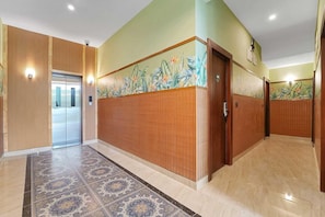 A hallway with a patterned carpet, wooden paneling, and a mural with tropical plants.