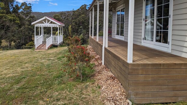 A house with a wooden deck and a covered porch. - Mountain Blue Guest house (Golden Valley)