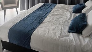 Een moderne hotelkamer met een groot bed, uitzicht op zee en een stoel bij het raam.