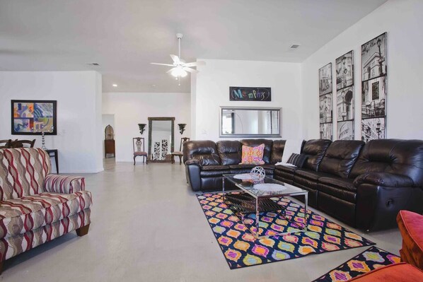 A spacious living room with a leather sofa, patterned armchair, and a coffee table.