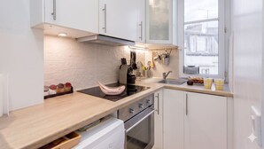 Ett modernt kök med vita skåp, en inbyggd ugn och ett fönster med utsikt över gatan.