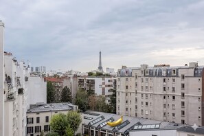 A cityscape with high-rise buildings, a prominent tower in the distance, and a banana-shaped structure on one building. - Charming Studio with Eiffel Tower Views in Paris's 15th (Paris)