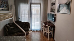 A room with a bed, a desk, a chair, a TV, and a window with curtains. - Waterfront Family Apartment (Thessaloniki city)