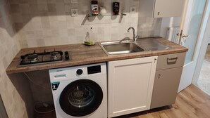 A compact kitchen with a washing machine, a sink, and a stove. - Waterfront Family Apartment (Thessaloniki city)