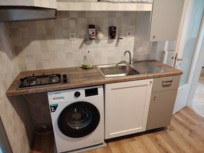 A compact kitchen with a washing machine, a sink, and a stove. - Waterfront Family Apartment (Thessaloniki city)