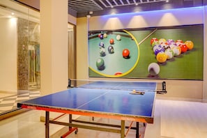 Une table de ping-pong avec une table de billard en arrière-plan.