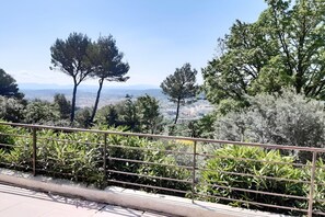 A balcony with a metal railing overlooking a cityscape with trees and distant mountains. - Villa with private pool, garden & panoramic views (Draguignan)