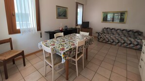 Un coin repas avec une table et des chaises, un canapé, un téléviseur et un tableau encadré au mur.