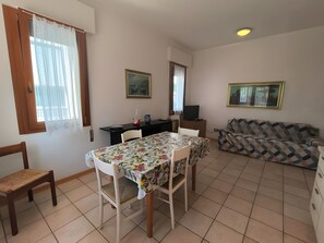 Ein Essbereich mit Tisch, Stühlen, einer Couch, einem Fernseher und einem gerahmten Bild an der Wand.